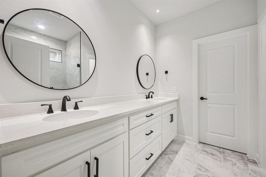 Full bathroom featuring double vanity, marble finish floors, and a marble finish shower Full bathroom featuring double vanity, marble finish floors, and a marble finish shower