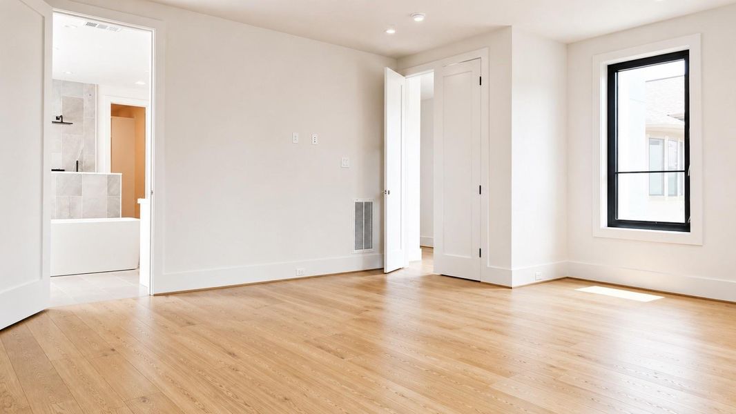 Primary Bath with wood flooring, high ceilings, and large windows.
