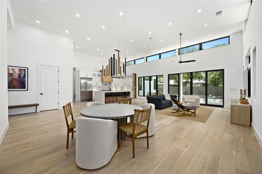 Dining room with recessed lighting, light wood-type flooring, a high ceiling, and visible vents
