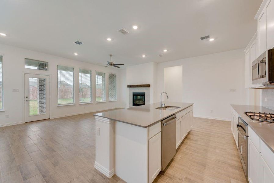 Kitchen featuring appliances with stainless steel finishes, sink, a kitchen island with sink, white cabinetry, and ceiling fan