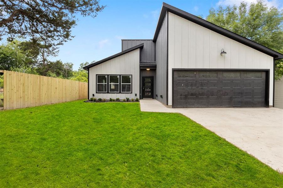 Modern farmhouse featuring a garage and a front lawn