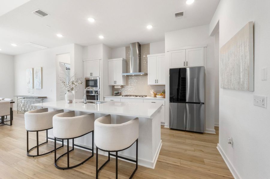 Kitchen with a sink, visible vents, appliances with stainless steel finishes, and wall chimney exhaust hood