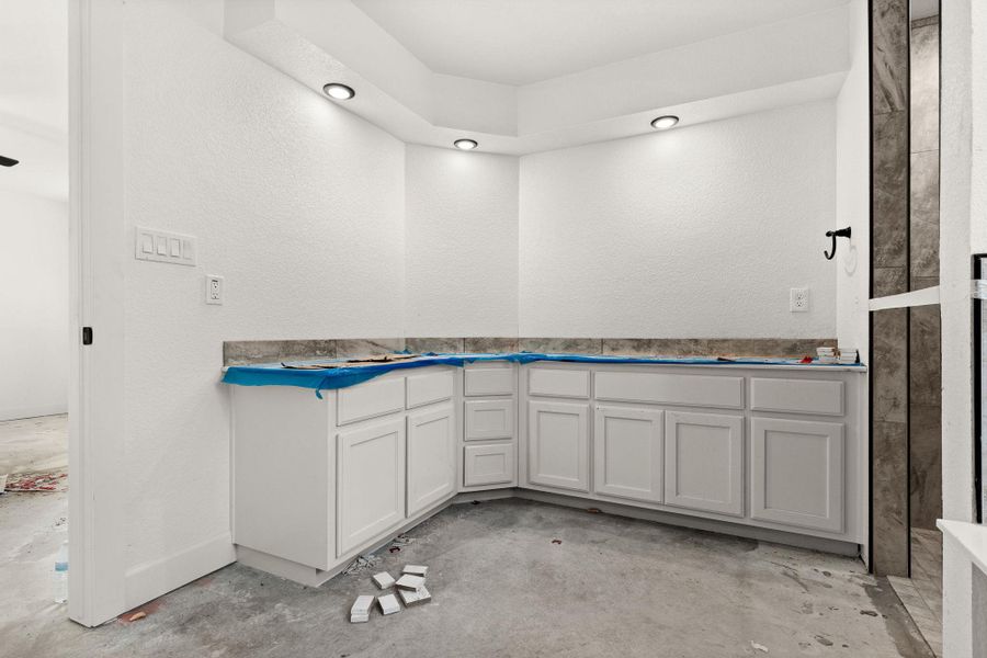 Full bath featuring concrete flooring and a textured wall Full bath featuring concrete flooring and a textured wall