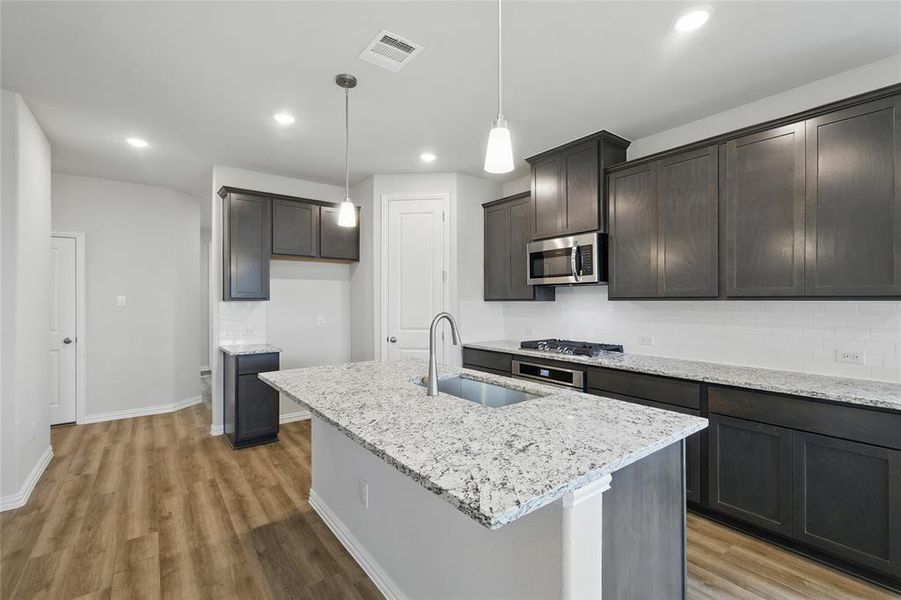 Kitchen featuring appliances with stainless steel finishes, light wood-style flooring, light stone counters, pendant lighting, and recessed lighting Kitchen featuring appliances with stainless steel finishes, light wood-style flooring, light stone counters, pendant lighting, and recessed lighting