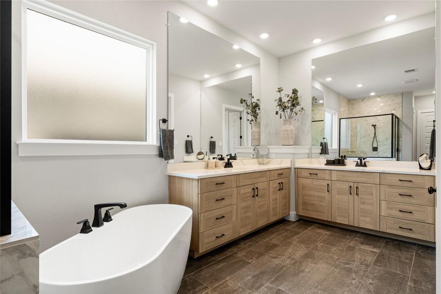 Luxurious primary bath with a freestanding tub and expansive vanity mirrors. Luxurious primary bath with a freestanding tub and expansive vanity mirrors.