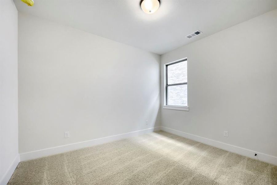 Neutral-toned interior room featuring light-colored carpeting, white baseboards, and a single window with a white frame Neutral-toned interior room featuring light-colored carpeting, white baseboards, and a single window with a white frame