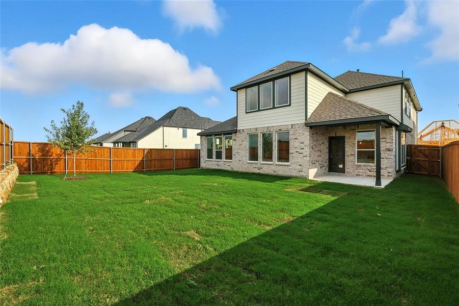 Rear view of house featuring a fenced backyard, brick siding, roof with shingles, and a patio area