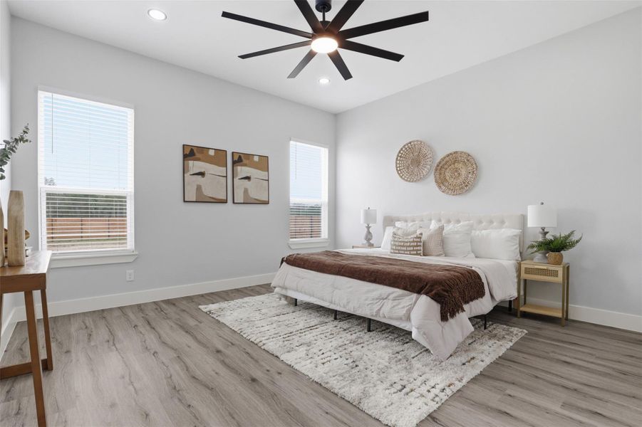 Spacious bedroom featuring light gray walls and wood-finish flooring