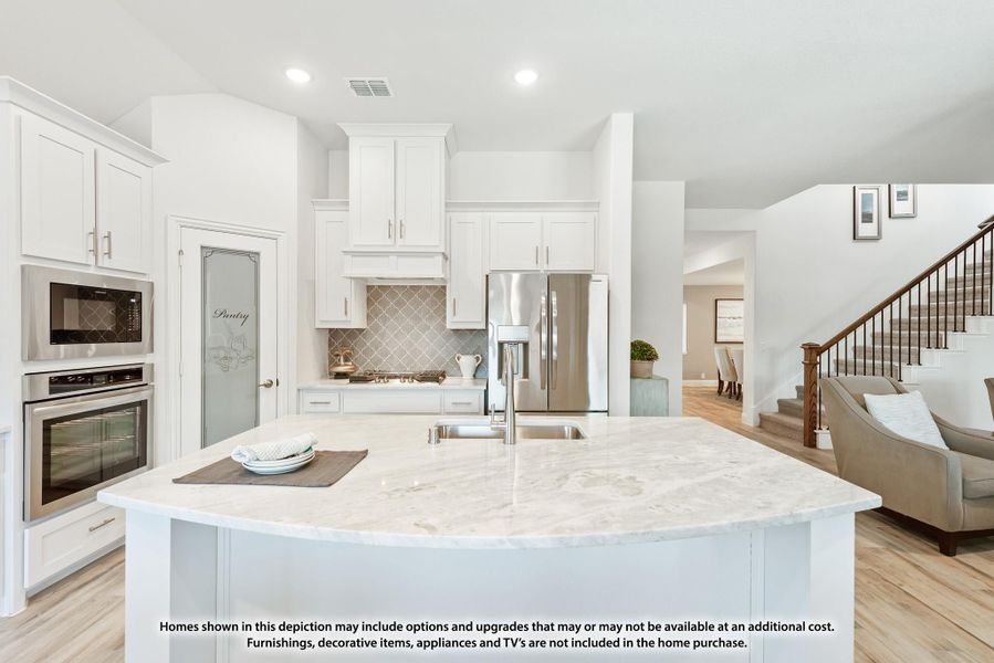 Kitchen with large marble island, white cabinets, stainless steel appliances, and tile backsplash open to living area with staircase Kitchen with large marble island, white cabinets, stainless steel appliances, and tile backsplash open to living area with staircase