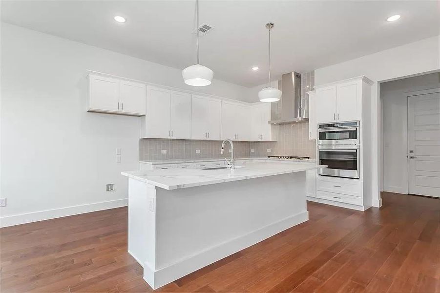 Kitchen featuring appliances with stainless steel finishes, white cabinets, backsplash, dark hardwood / wood-style floors, and wall chimney exhaust hood