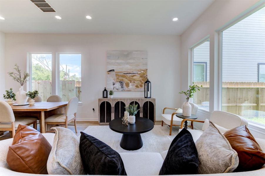 Living room back wall with rear exit door, vertical window, hardwood floors, and recessed lighting. Clean, open layout.