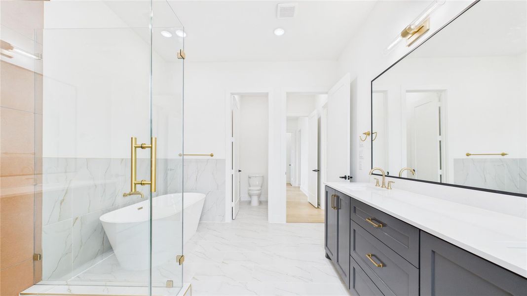 The double vanity has plenty of storage with sleek black cabinetry and gold fixtures.