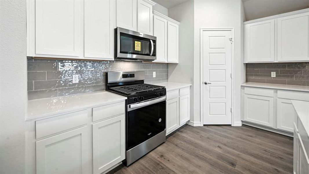Kitchen featuring white cabinetry, light countertops, a stainless steel range, and a coordinating microwave Kitchen featuring white cabinetry, light countertops, a stainless steel range, and a coordinating microwave