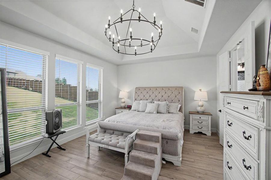 Vaulted ceiling with an iron chandelier, wood-finish flooring, and multiple windows
