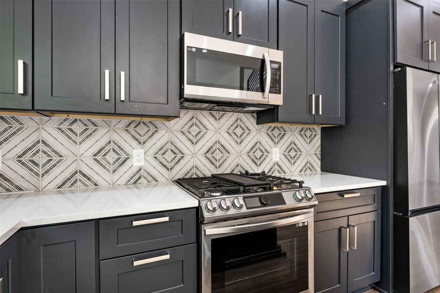 Kitchen with appliances with stainless steel finishes, decorative backsplash, and light stone countertops