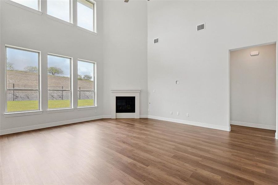 Unfurnished living room featuring wood-type flooring and a towering ceiling