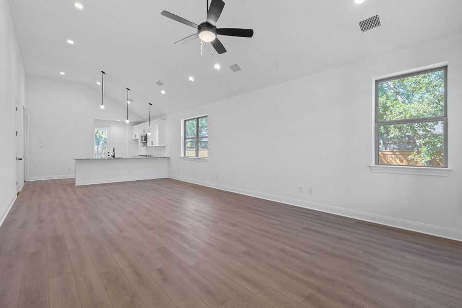 Unfurnished living room with dark wood-style floors, recessed lighting, high vaulted ceiling, and a ceiling fan