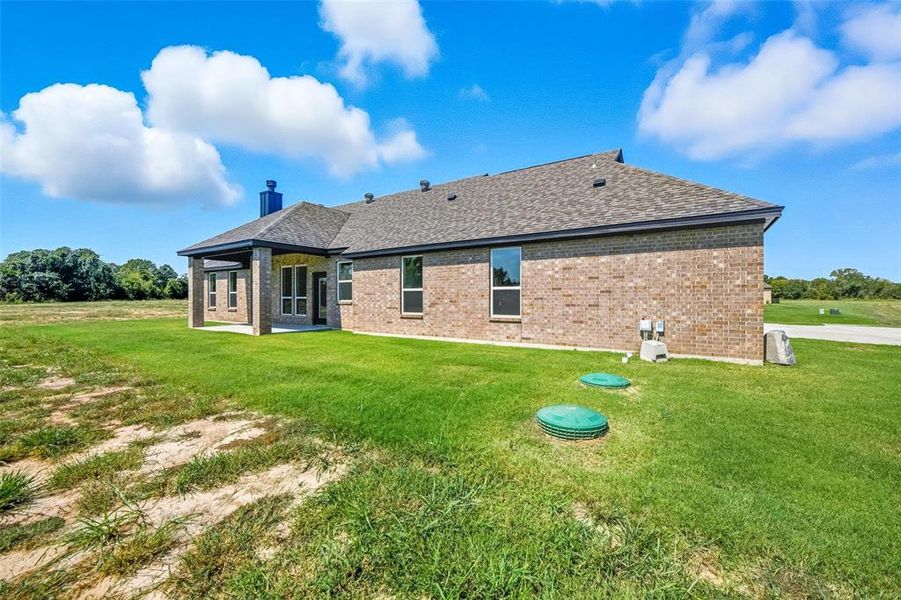 Rear view of house featuring a patio, brick siding, a shingled roof, and a lawn Rear view of house featuring a patio, brick siding, a shingled roof, and a lawn