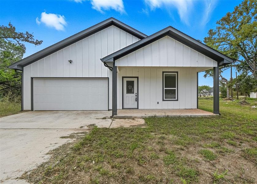 Modern farmhouse with a porch, board and batten siding, concrete driveway, a front lawn, and a garage Modern farmhouse with a porch, board and batten siding, concrete driveway, a front lawn, and a garage