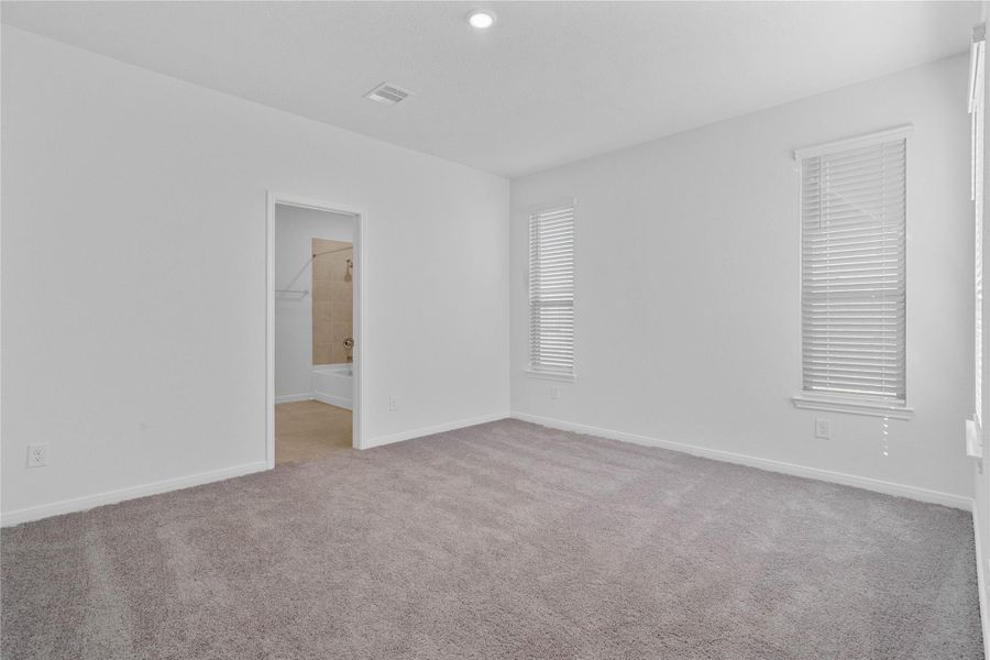 Relax and recharge in this stunning primary suite! Enjoy the comfort of plush carpeting, neutral toned walls, high ceilings, and windows that fill the room with natural light.