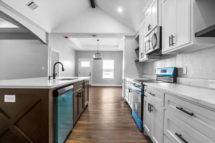 Kitchen featuring white cabinets, decorative light fixtures, sink, and appliances with stainless steel finishes