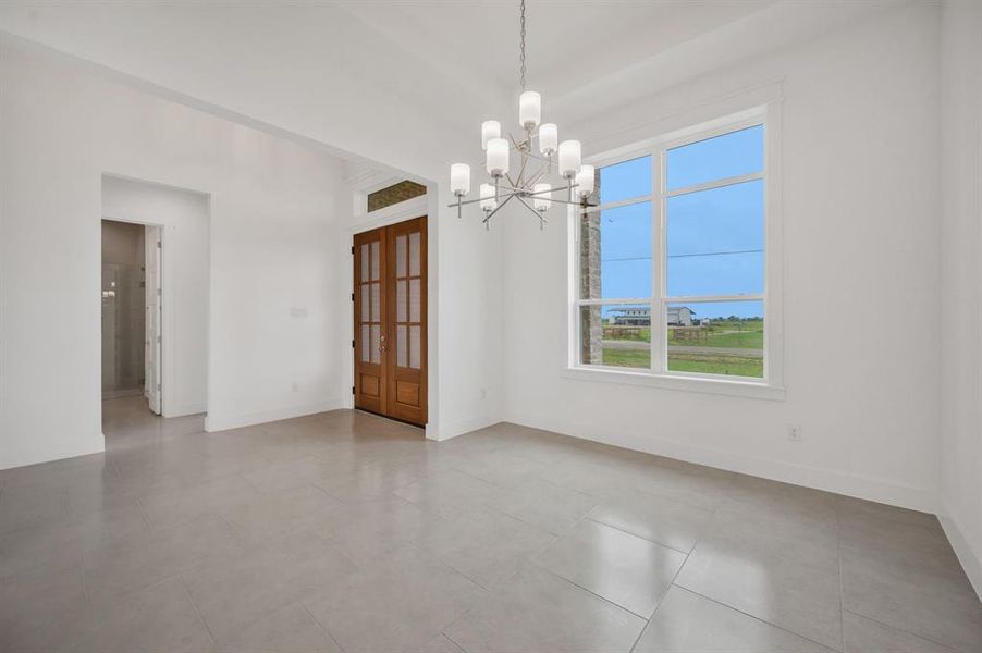 Empty room featuring baseboards and a notable chandelier Empty room featuring baseboards and a notable chandelier