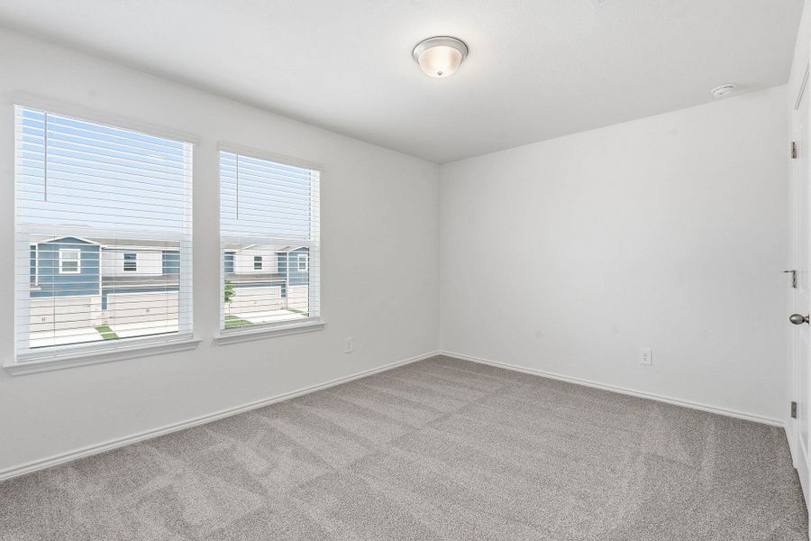 Room featuring two large windows with blinds, light gray wall-to-wall carpeting, white painted walls, and a ceiling-mounted light fixture Room featuring two large windows with blinds, light gray wall-to-wall carpeting, white painted walls, and a ceiling-mounted light fixture