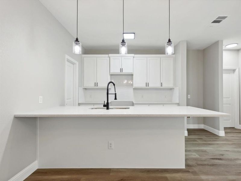 Kitchen with white cabinets, hardwood / wood-style floors, and decorative light fixtures