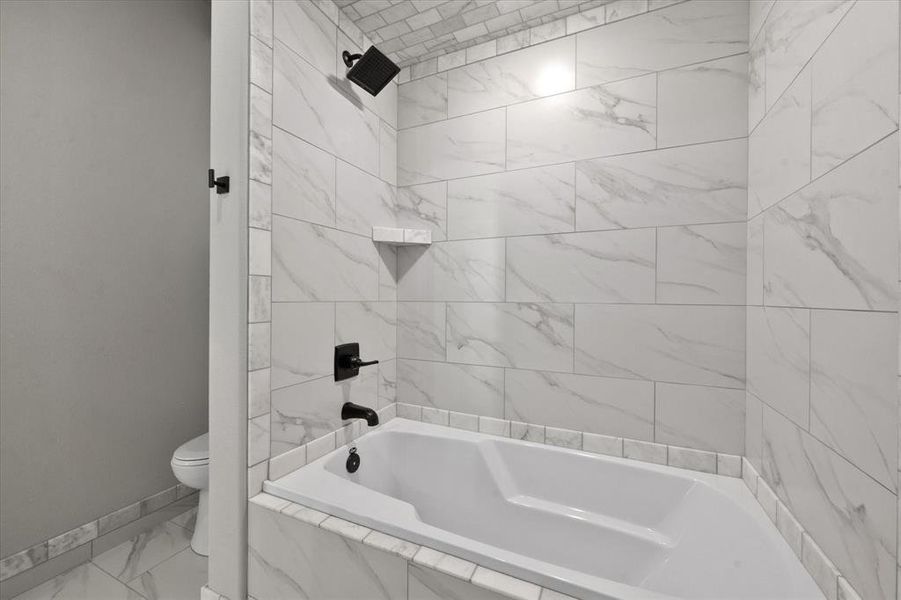 Bathroom with toilet and tiled shower / bath combo