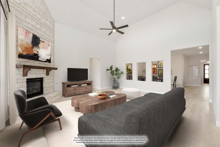 Living room with vaulted ceiling, stone fireplace, ceiling fan, and light wood floors