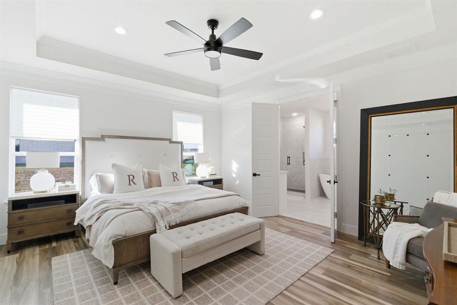Bedroom featuring a tray ceiling, light wood-type flooring, ceiling fan, ornamental molding, and recessed lighting