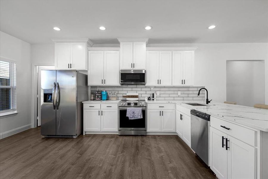 Kitchen featuring appliances with stainless steel finishes, white cabinets, backsplash, recessed lighting, and dark wood-style flooring Kitchen featuring appliances with stainless steel finishes, white cabinets, backsplash, recessed lighting, and dark wood-style flooring