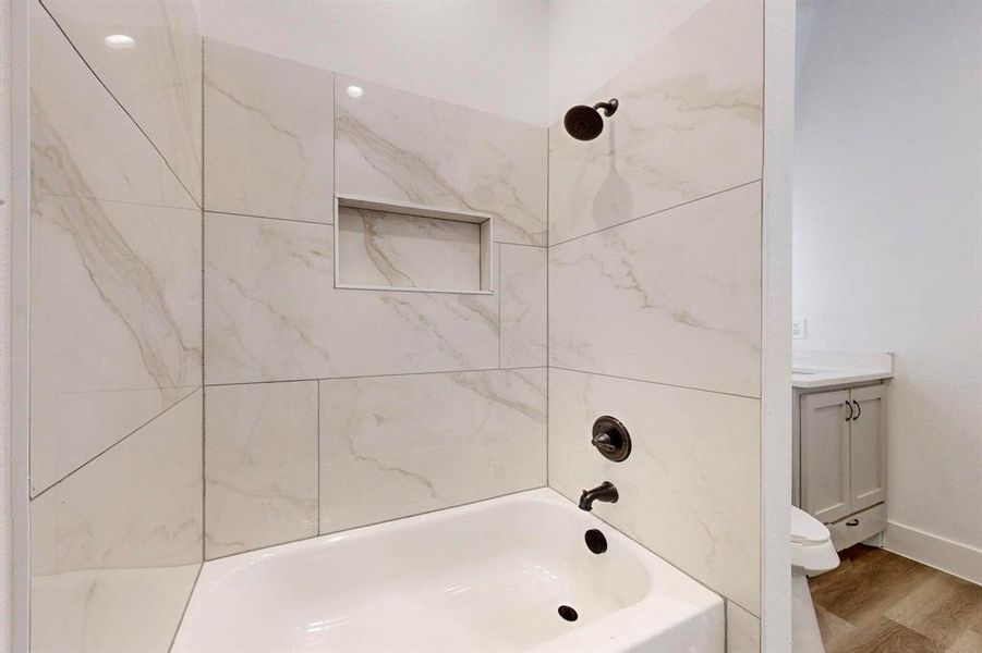 Full bathroom featuring toilet, vanity, hardwood / wood-style flooring, and tiled shower / bath combo