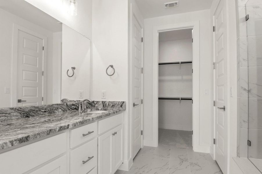Full bath with light marble finish floors, vanity, and a marble finish shower Full bath with light marble finish floors, vanity, and a marble finish shower
