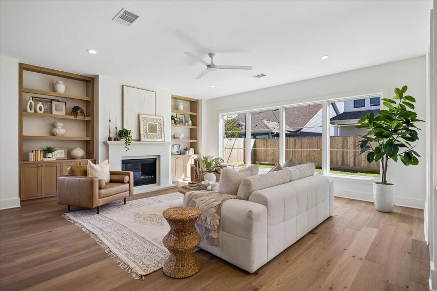 Natural light pours through oversized picture windows, casting warmth across wide plank hardwood floors and the clean lined fireplace.**PREVIOUS BUILDER WORK** Natural light pours through oversized picture windows, casting warmth across wide plank hardwood floors and the clean lined fireplace.**PREVIOUS BUILDER WORK**
