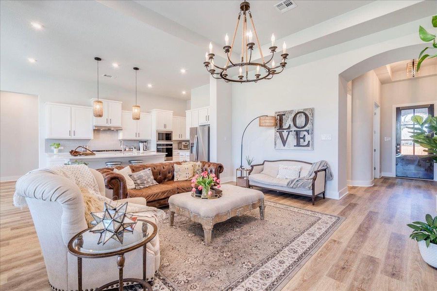 Living area with arched walkways, suspended lighting, and light wood finished floors Living area with arched walkways, suspended lighting, and light wood finished floors