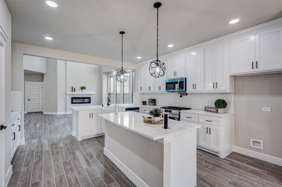 Kitchen with a peninsula, recessed lighting, wood tiled floors, stainless steel appliances, and white cabinets