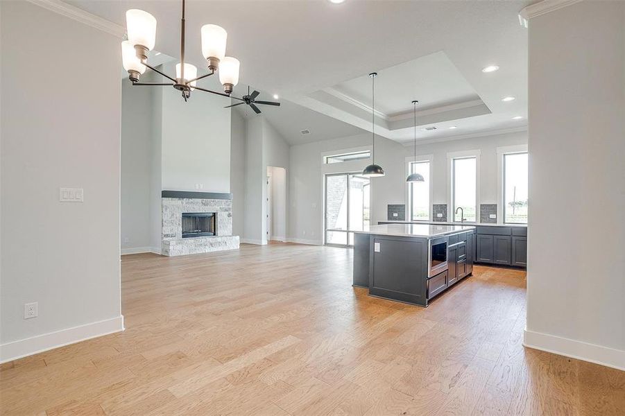 Kitchen featuring hanging light fixtures, ceiling fan with notable chandelier, a fireplace, light hardwood / wood-style floors, and a center island