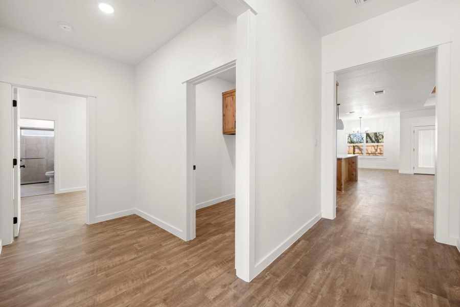 A flowing layout with warm wood-look flooring connects various bright living areas.