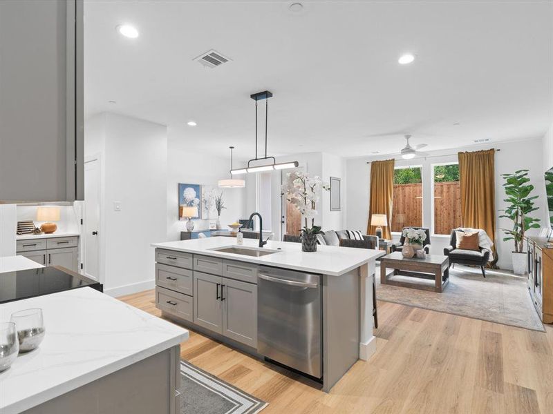 Kitchen with a sink, gray cabinets, light wood-type flooring, stainless steel dishwasher, and visible vents Kitchen with a sink, gray cabinets, light wood-type flooring, stainless steel dishwasher, and visible vents