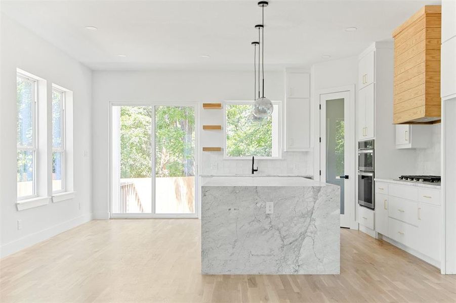 Kitchen featuring light hardwood / wood-style floors, backsplash, white cabinetry, and appliances with stainless steel finishes