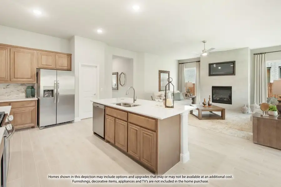 Open-concept kitchen with center island, wood cabinets, stainless appliances, and living room with fireplace in background. Open-concept kitchen with center island, wood cabinets, stainless appliances, and living room with fireplace in background.