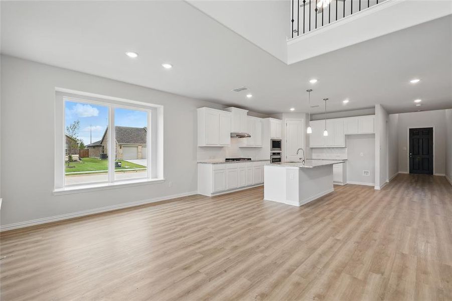 Unfurnished living room featuring light wood-style floors, baseboards, recessed lighting, and a sink Unfurnished living room featuring light wood-style floors, baseboards, recessed lighting, and a sink