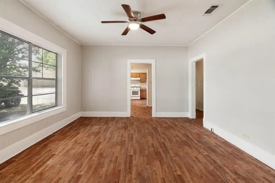 Empty room with ornamental molding, dark wood-style floors, a ceiling fan, and wooden walls Empty room with ornamental molding, dark wood-style floors, a ceiling fan, and wooden walls