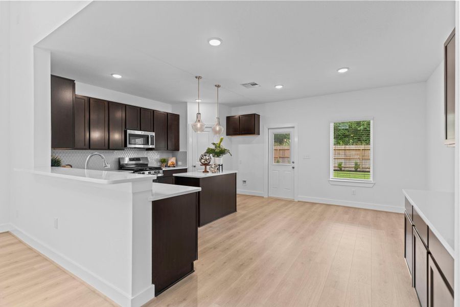 The kitchen opens beautifully into the main living space, showcasing a modern layout with wood-like vinyl plank flooring, pendant lighting, and ample counter space for both meal prep and casual gatherings. **Image Representative of Plan Only and May Vary as Built**.