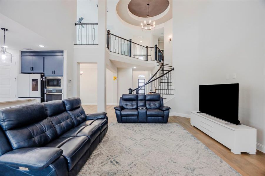 Living area featuring stairway, wood finished floors, baseboards, an inviting chandelier, and a towering ceiling