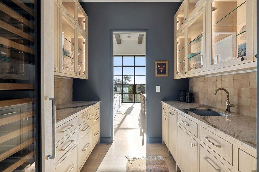 Kitchen featuring glass fronted cabinets, beverage cooler, decorative backsplash, and light stone counters