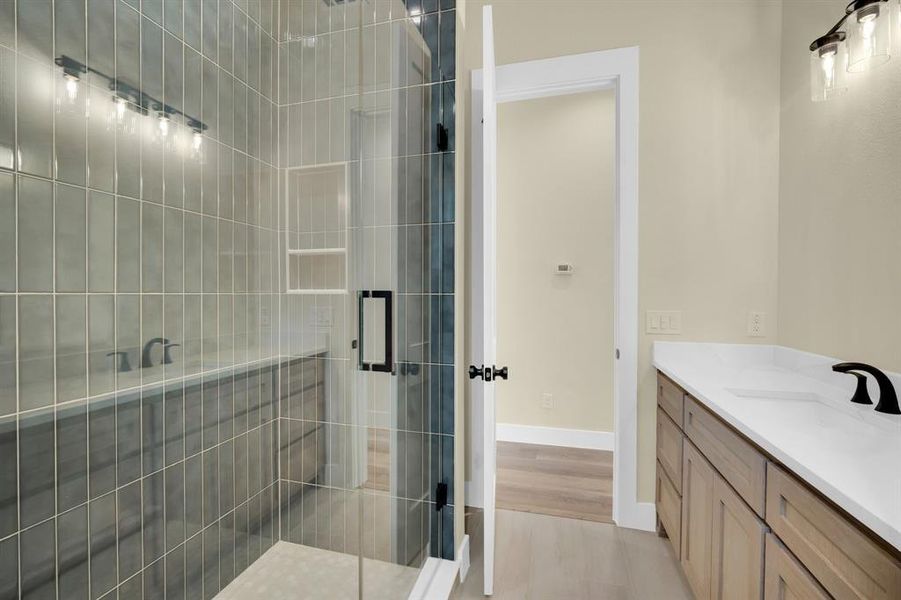 Bathroom featuring hardwood / wood-style flooring, vanity, and an enclosed shower