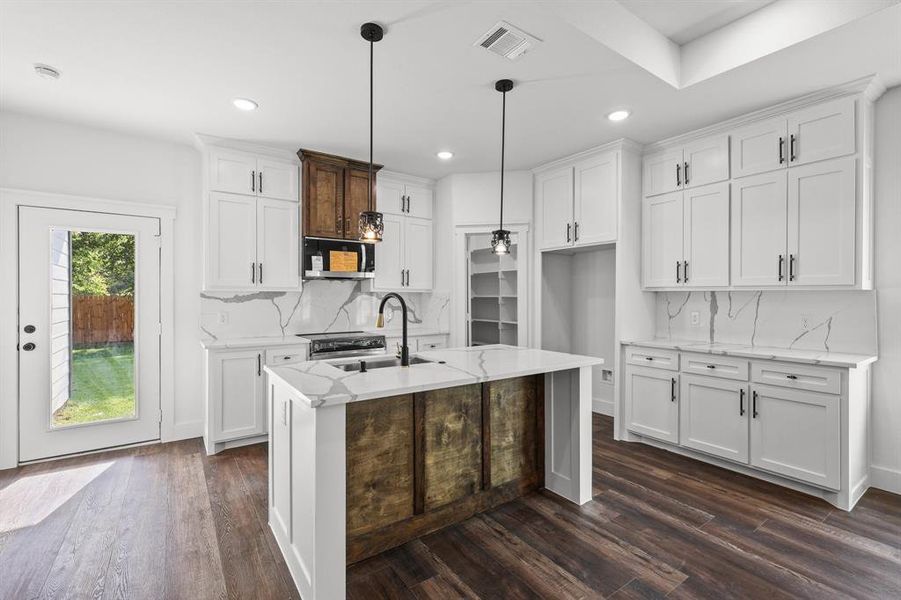 Kitchen featuring white cabinetry, stainless steel appliances, dark hardwood / wood-style flooring, light stone countertops, and hanging light fixtures