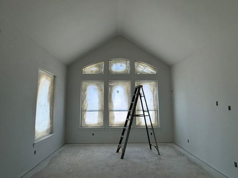An inviting room under construction boasts vaulted ceilings and generous window placements, awaiting finishing touches. An inviting room under construction boasts vaulted ceilings and generous window placements, awaiting finishing touches.